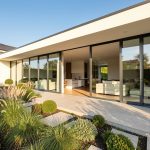 Maison neuve contemporaine lumineuse avec grandes baies vitrées et jardin soigneusement aménagé.